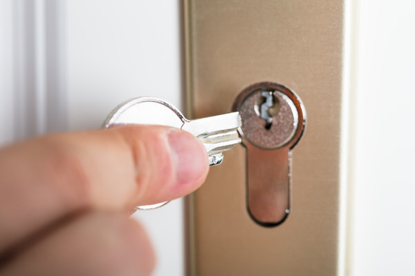 Close-up Of Person's Hand Holding Broken Key Inserting In Keyhole