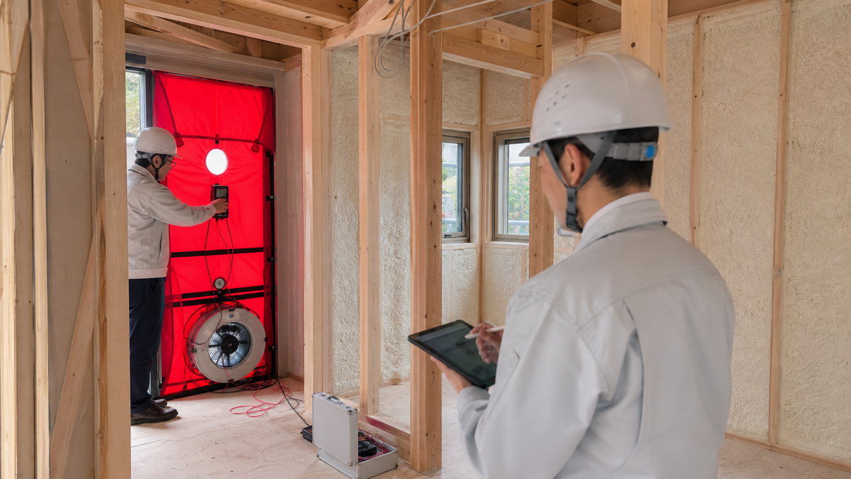 建築中の住宅で気密測定と断熱施工を確認する様子