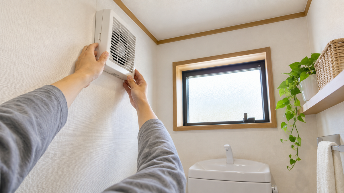 トイレの壁付け換気扇を確認する様子